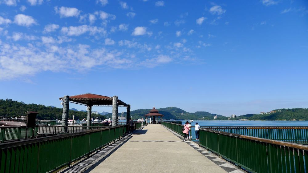 Three people stand on Itathao Pier, Sun Moon Lake
