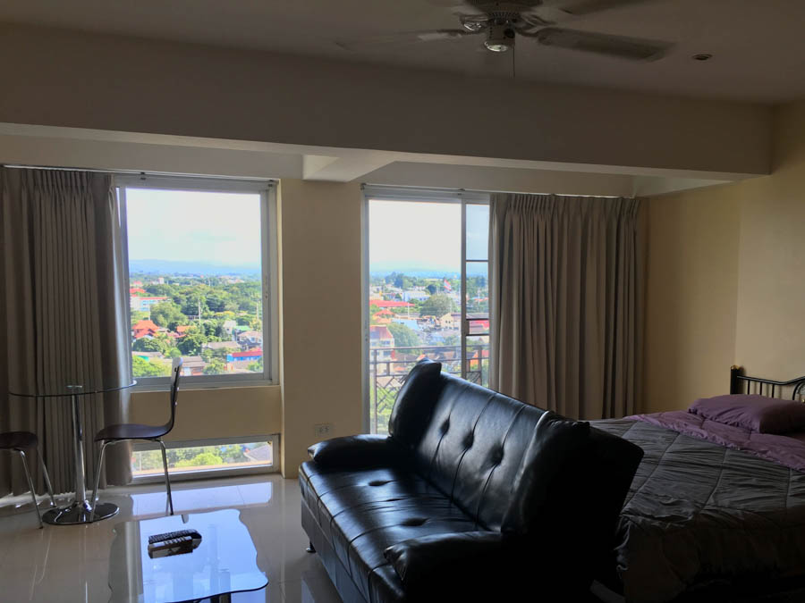 A studio apartment in the Chang Khlan neighborhood with a table, a sofa, a bed, and a view of the mountains.