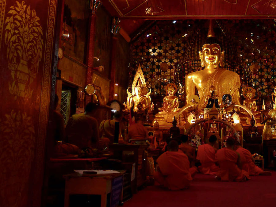 Novice monks sit in front of Buddha statue at War Phra That Doi Suthep.