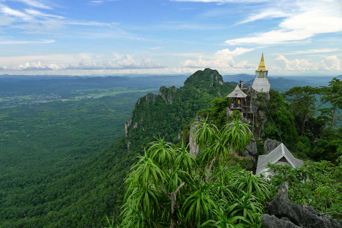 People climb stairs at Wat Chaloem Phrakiat Phrachomklao Rachanusorn temple complex (also known as the "Floating Pagodas") surrounded by limestone karst scenery.