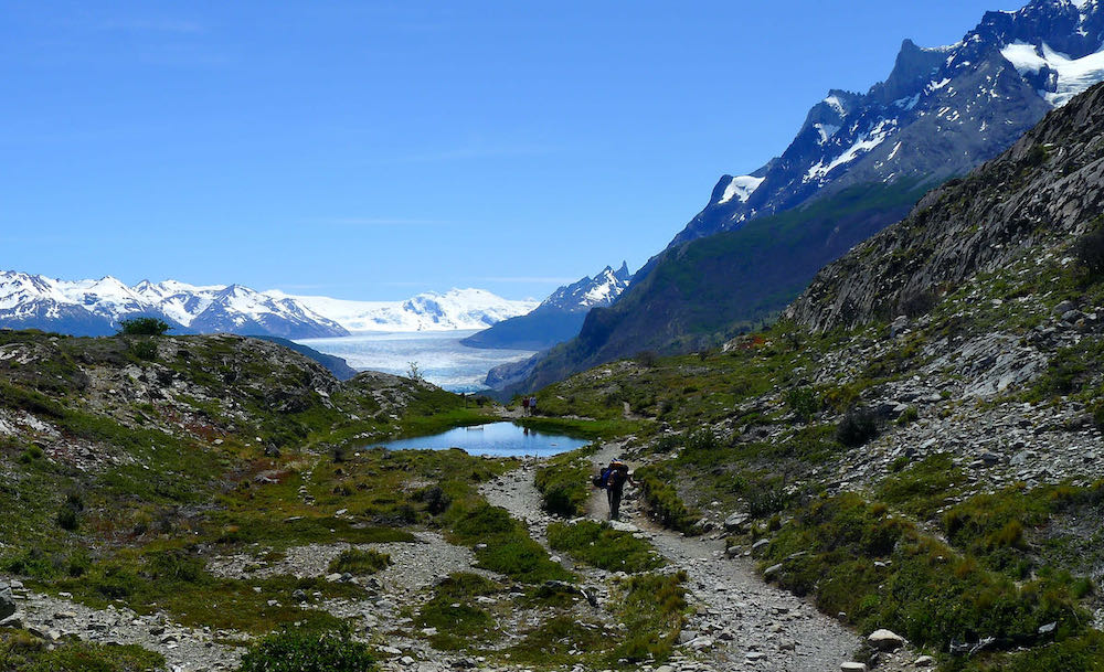 A person hikes on the W Trek in Torres del Paine National Park with Grey Glacier in the background.