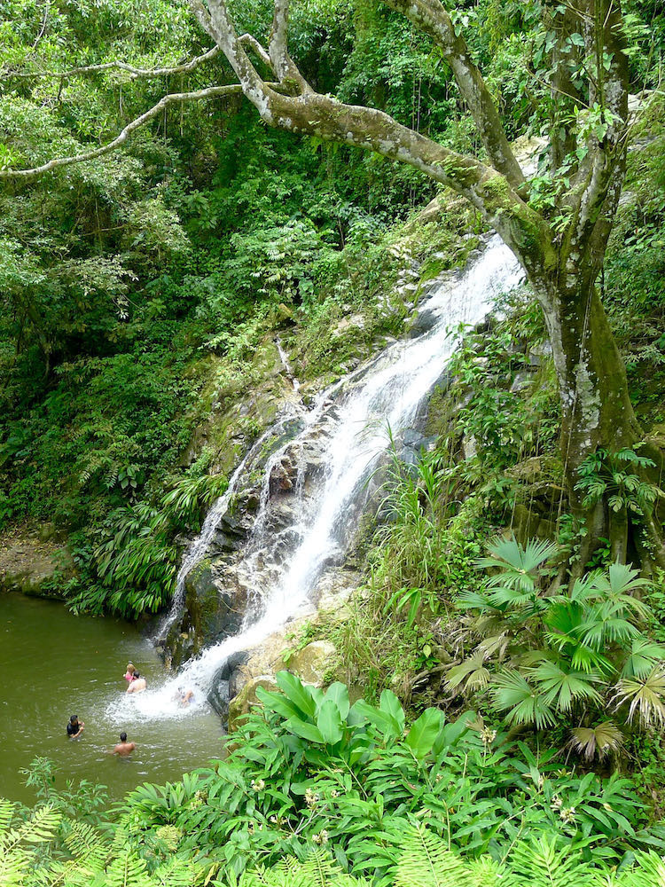 View of people swimming under Marinka Waterfalls from above.