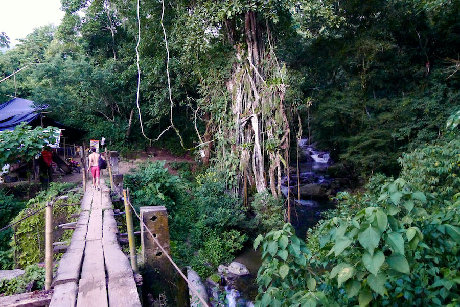 A person walks on a wooden bridge next to Pozo Azul waterfalls.