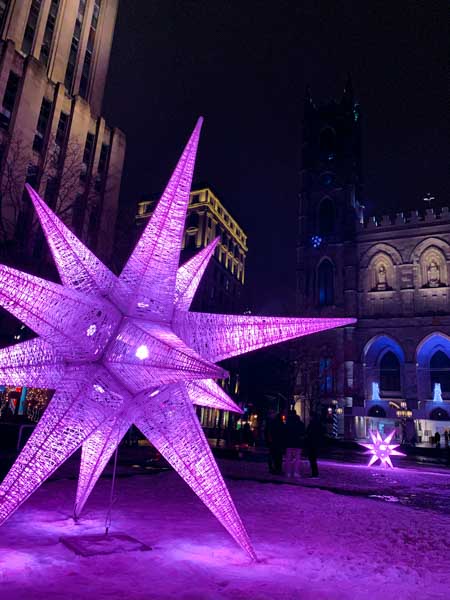 Colorful Christmas decorations in Place d'Armes, in front of Notre-Dame Basilica of Montreal, in December.