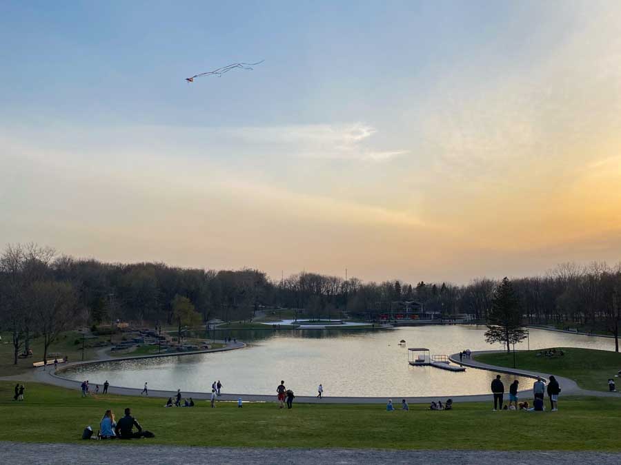 A kite flies over Lac Aux Castors in April as people watch the sunset and enjoy warmer weather.