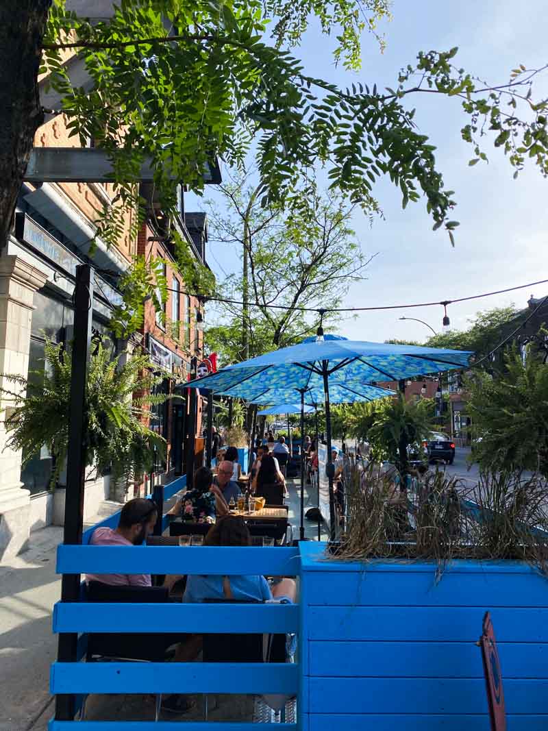 An outdoor terrace with umbrellas for the June sunshine on Rue Notre Dame in Little Burgundy.