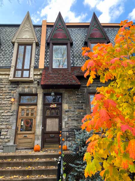 Pumpkins and bright fall foliage in front of unique Montreal homes in October.