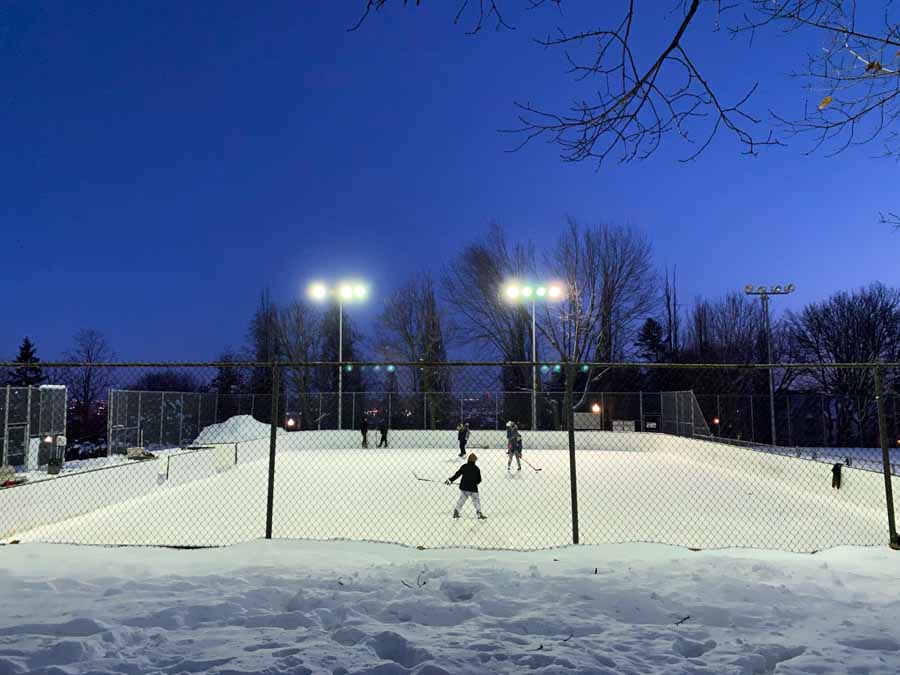 Teenagers play ice hockey at a neighborhood skating rink on a January evening in Montreal.