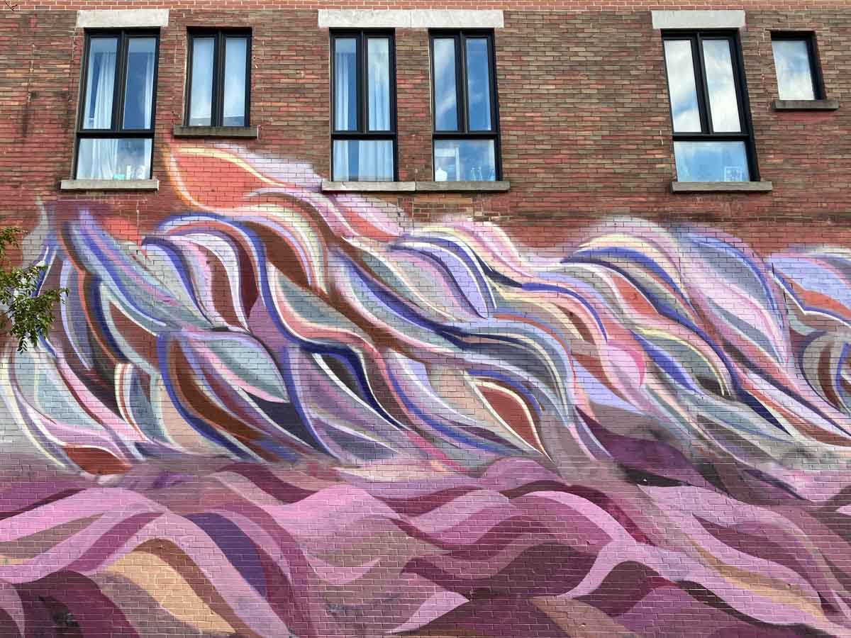 A large, pink and purple mural called "Martine" on a brick wall in the Plateau neighborhood in Montreal.