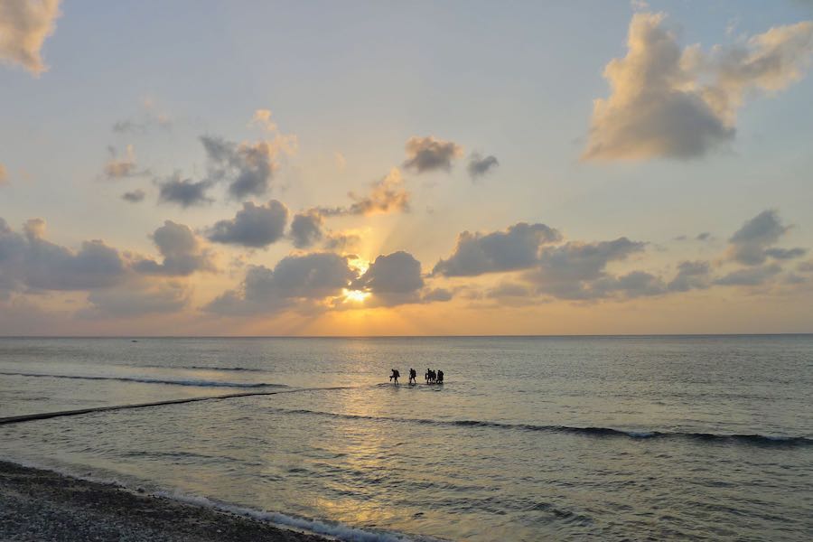 Scuba divers surface from a shore dive on Green Island at sunset.