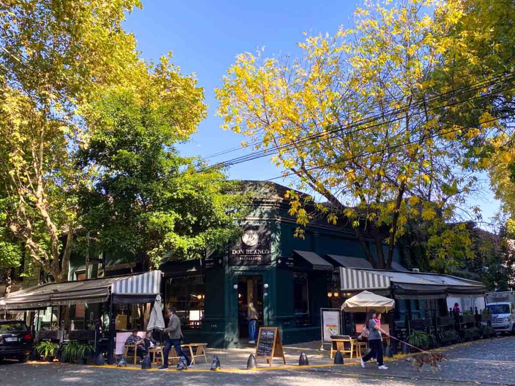 An autumn street scene in Palermo Hollywood with outdoor cafe seating along cobblestone streets.