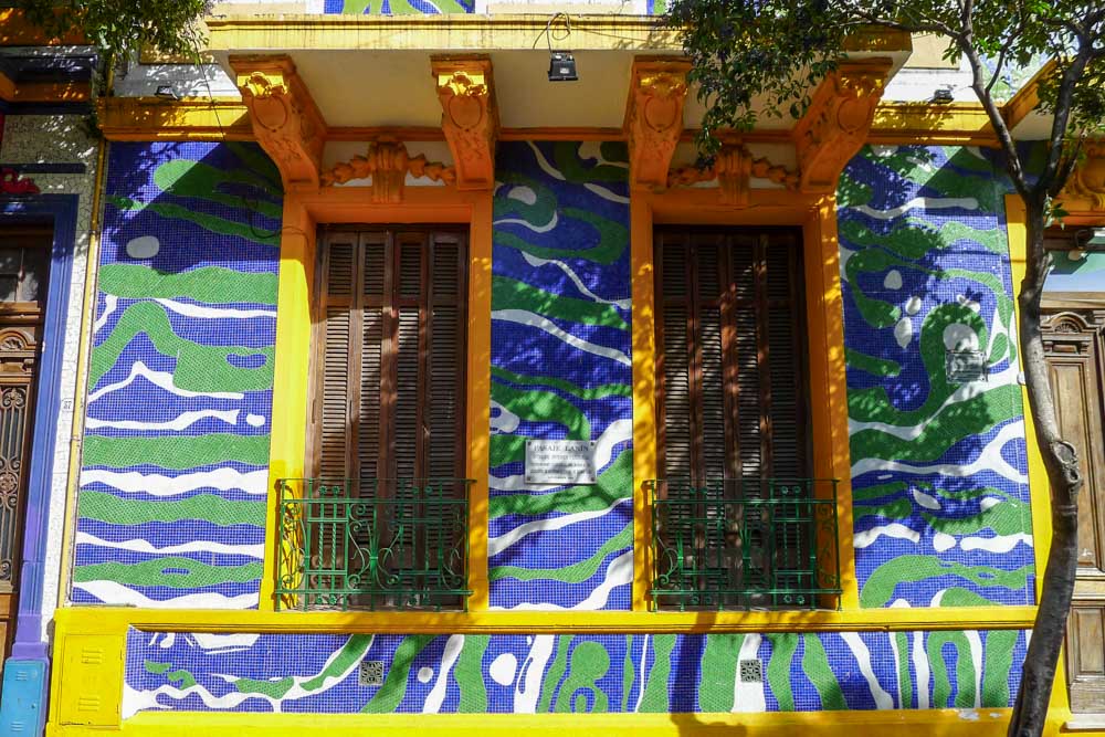 Blue, white, and green tiles decorate a building with yellow trim around the windows on Pasaje Lanín in Barracas.