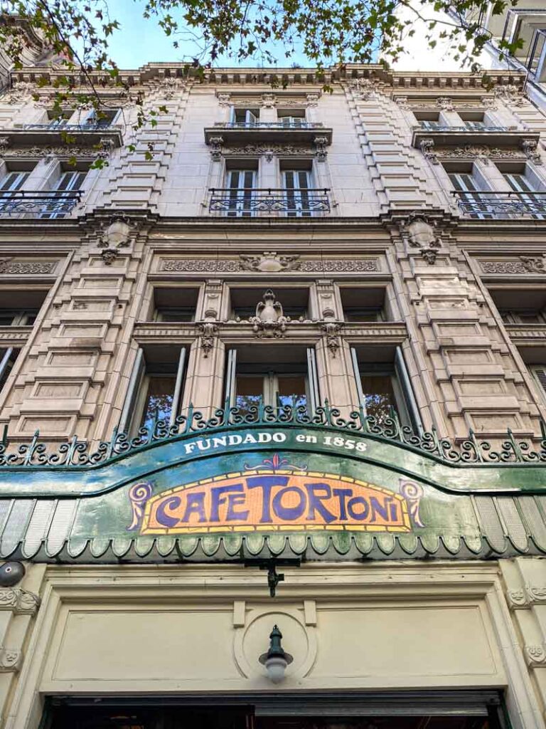 Looking up at the iconic green and orange Cafe Tortoni sign on Avenida de Mayo.