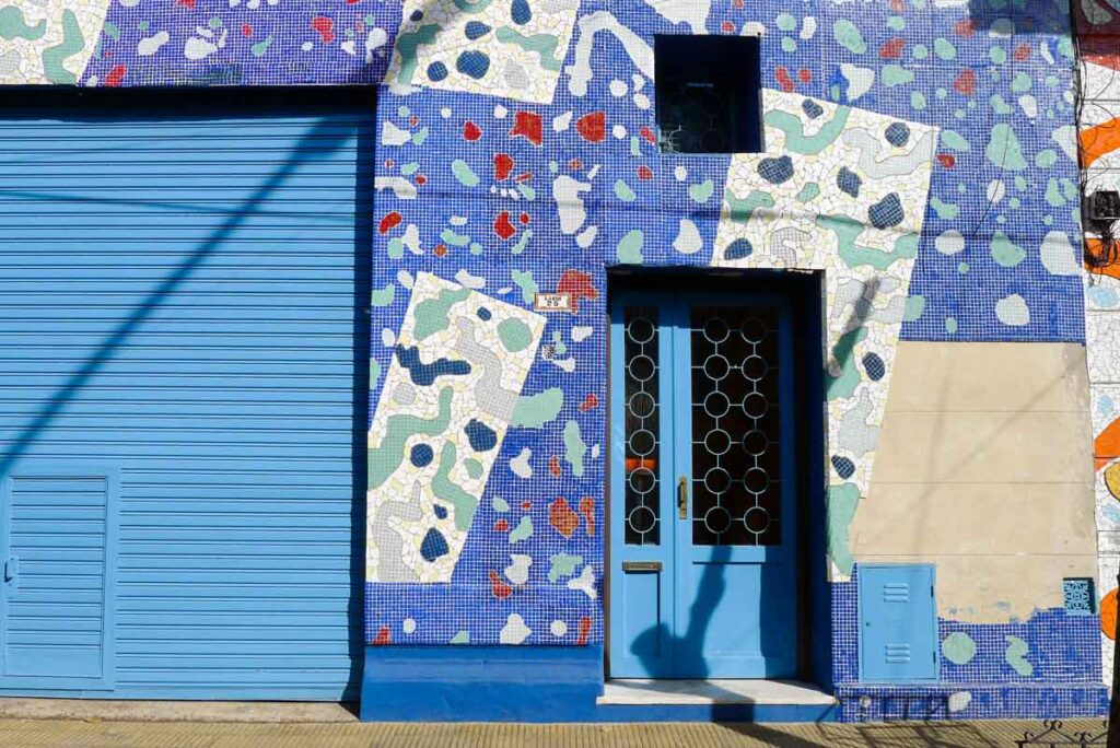 A blue door on Calle Lanín in Buenos Aires surrounded by colorful mosaic tiles.