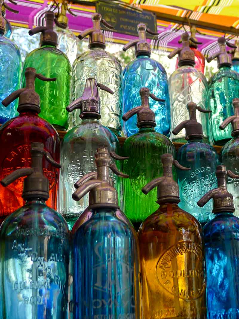 Colorful antique soda bottles on display at the Feria de San Telmo, a popular Sunday antique and handicraft market.