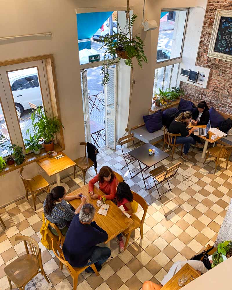 People dine in a cozy and bright cafe in Palermo Hollywood. The photo is taken from above on the stairs to second floor.