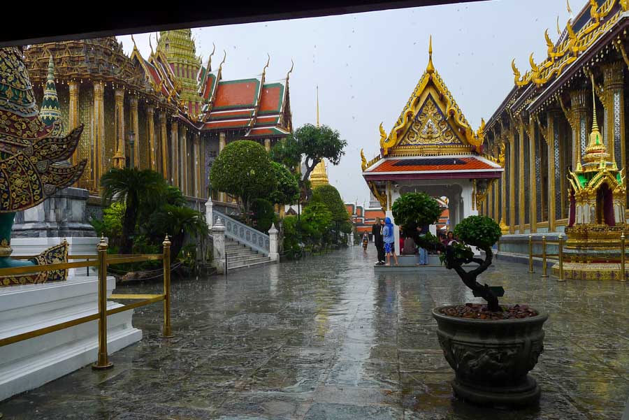 Hiding from a rainstorm at Bangkok's Grand Palace while traveling in Thailand during rainy season.