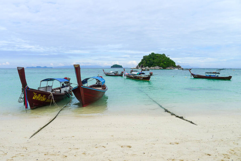 Longtail boats on Sunrise Beach on Koh Lipe with Koh Usen in the background.