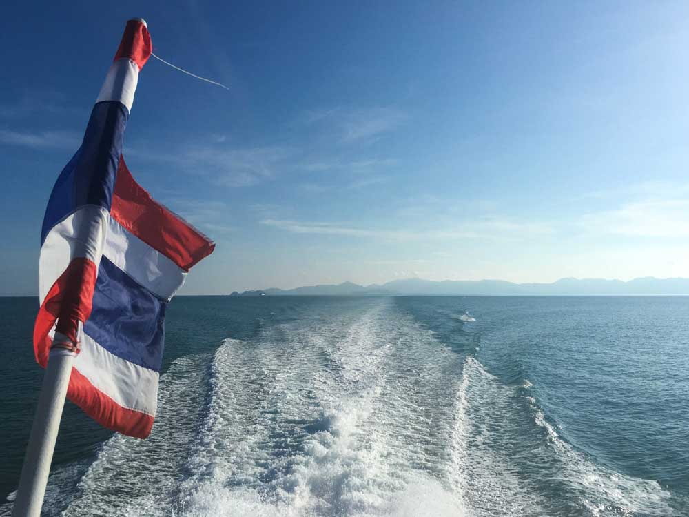 A Thailand flag blowing in the wind from the back of my ferry to Surat Thani.