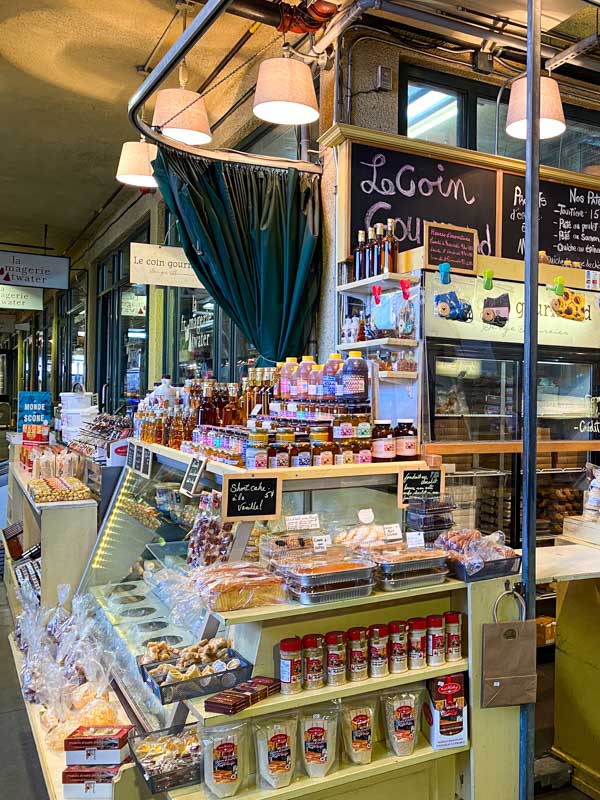 Indoor Atwater market stall selling jam, maple syrup, sauces, and baked goods.