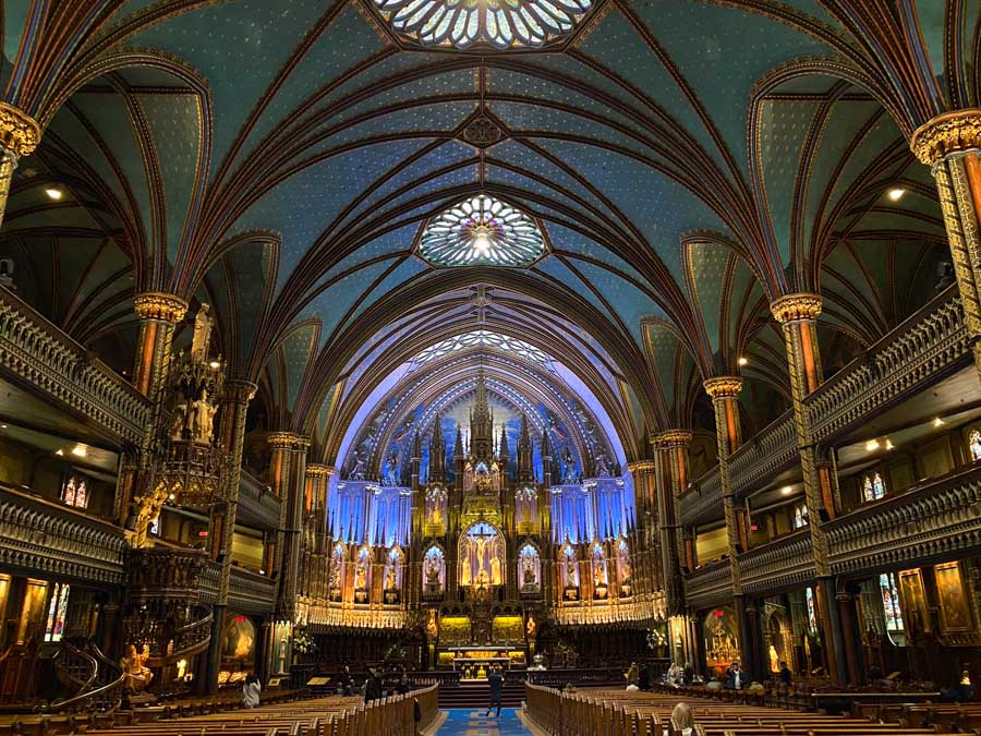 The stunning blue and gold interior of Notre-Dame Basilica in Montreal, with stained glass visible on the ceiling.