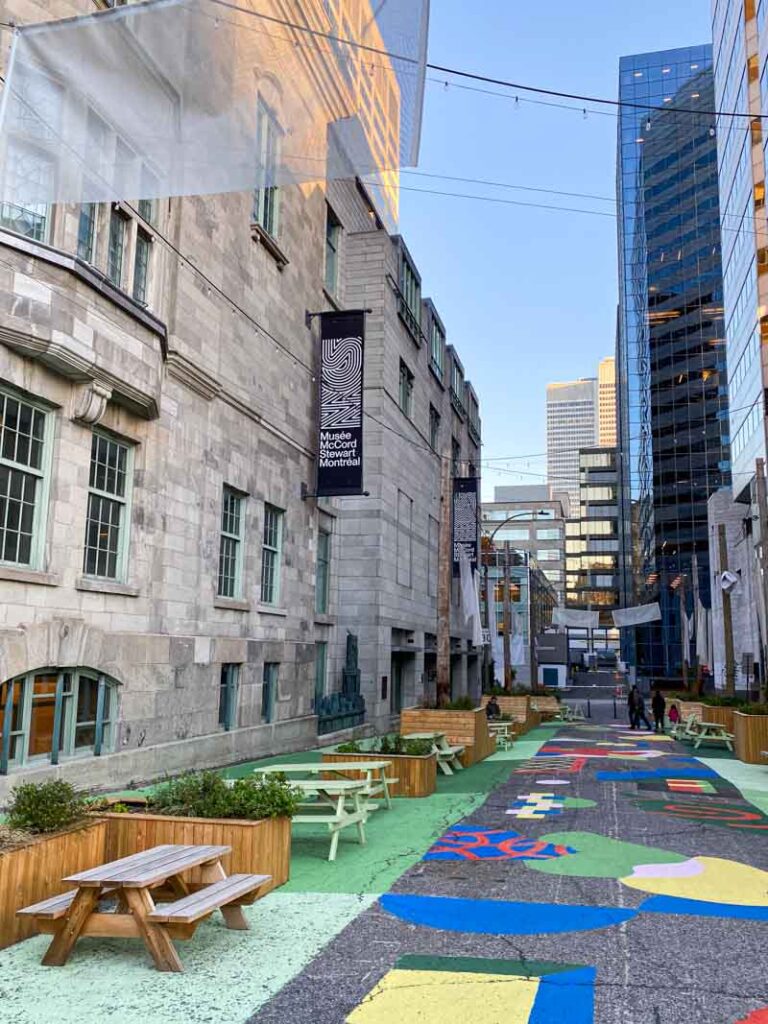 The colorfully painted lane with picnic tables and string lights next to the McCord Stewart Museum in downtown Montreal.