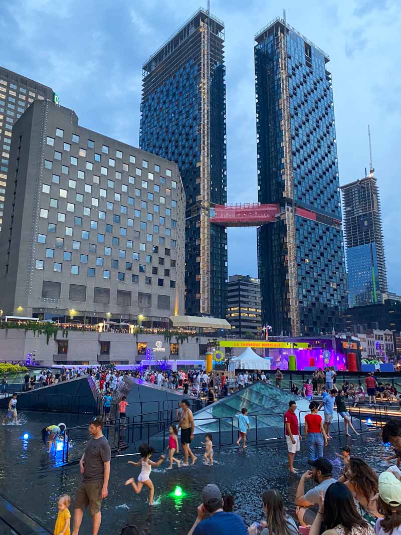 Families play in the Place des Arts fountain on a summer night between free performances during the Montreal International Jazz Festival.