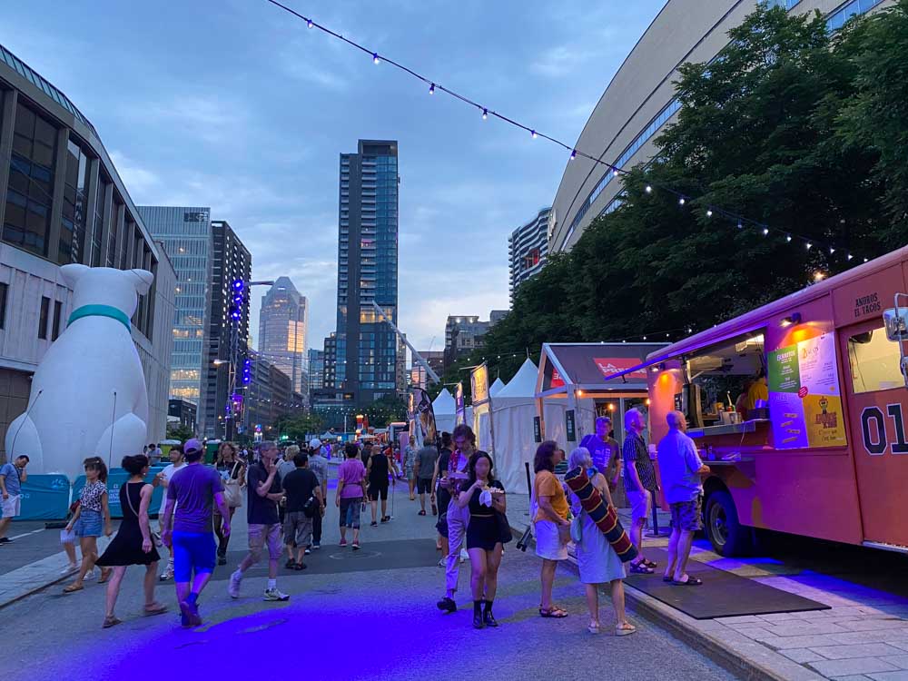 People walk and eat at food trucks during a summer festival night in Montreal's Quartier des Spectacles.