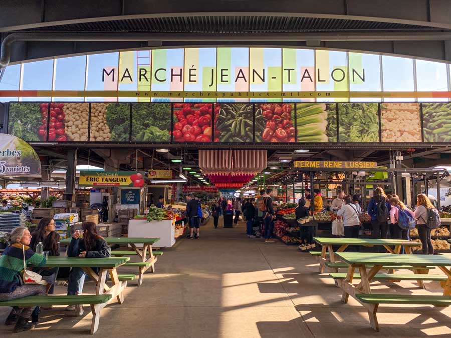 Picnic tables in front of fruit and vegetable stands at Jean-Talon Market.