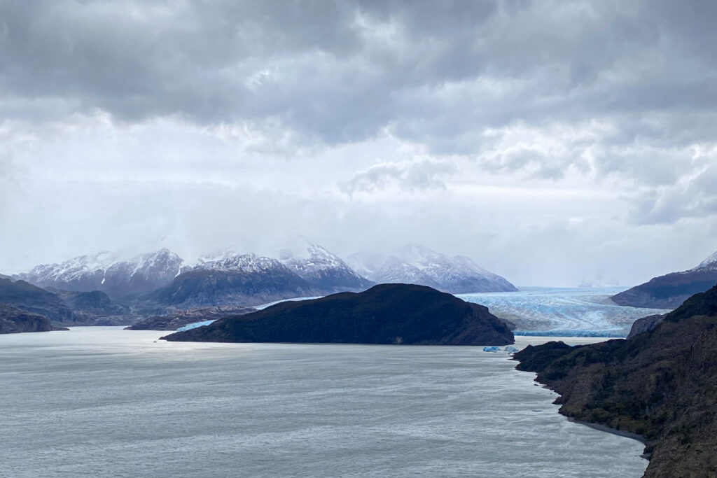 A distant view (from the hiking trail) of a tiny Grey Navigation ferry sailing from Grey Glacier to Refugio Grey.