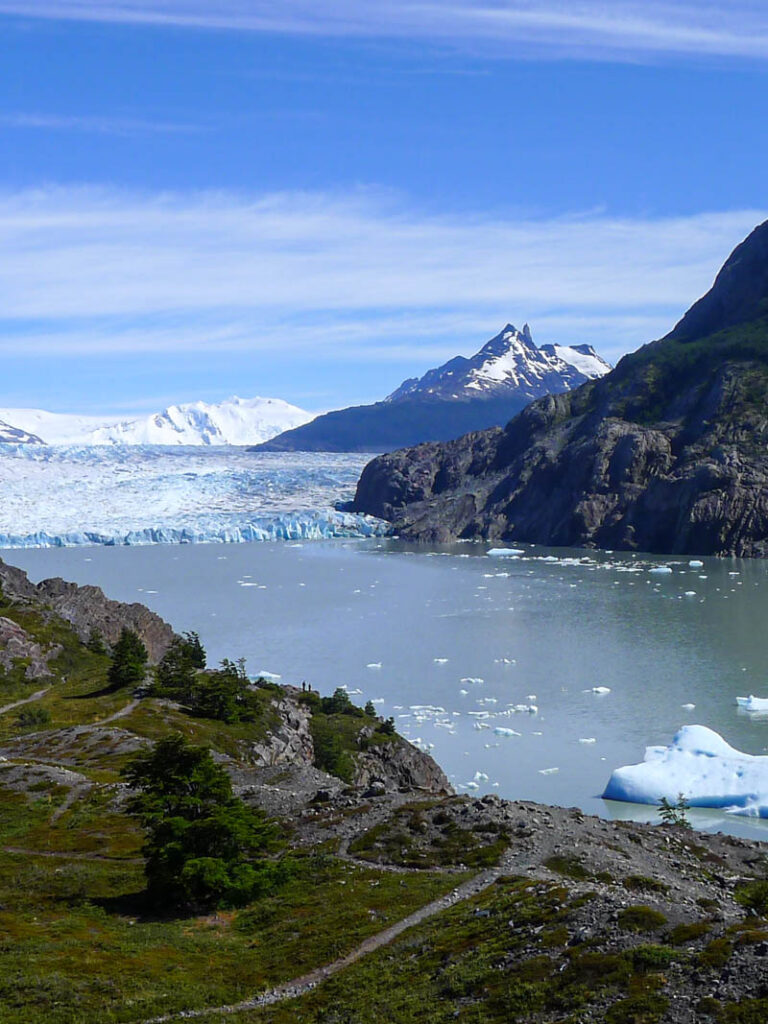 Two tiny people look out at Grey Glacier and icebergs in Lago Grey from the mirador closest to the refugio.