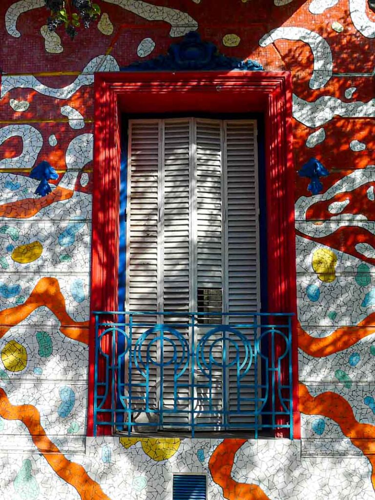Colorful mosaic tiles surrounding a window on Calle Lanín, a truly unique place to visit in Buenos Aires.