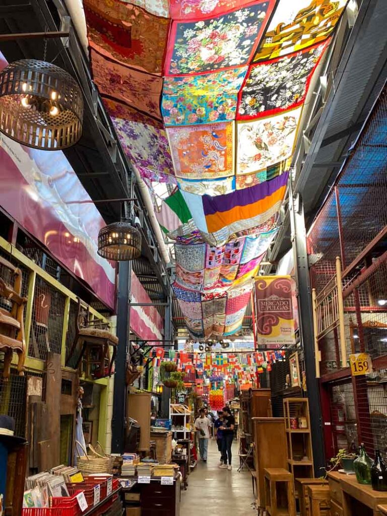 Exploring off the beaten path in Buenos Aires at the Mercado de Pulgas and looking up at a colorful patchwork tapestry.