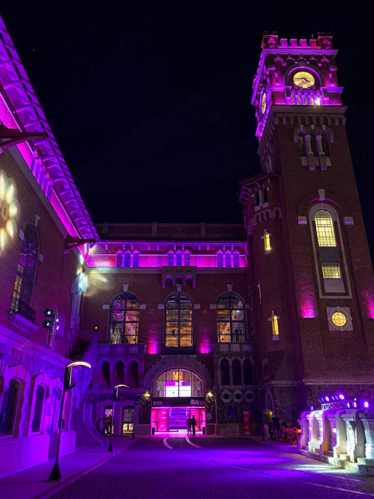Exterior of the Usina del Arte cultural center lit up with pink and purple lights at night.