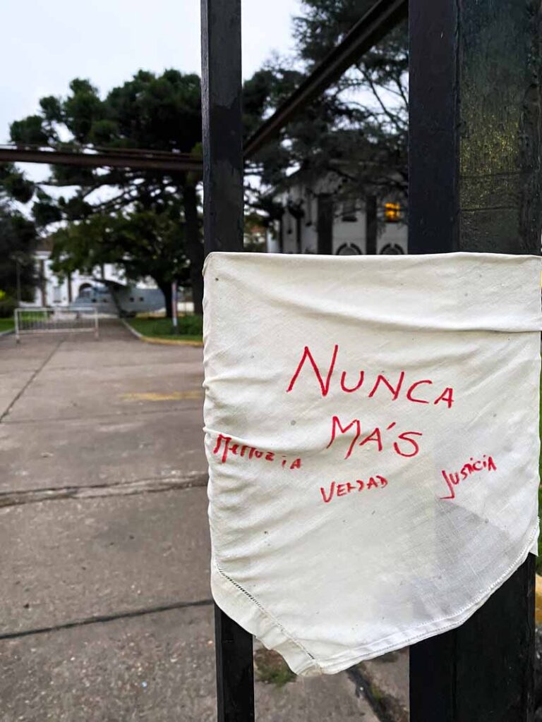 White scarf (like the ones typically worn by the Madres de Plaza de Mayo) tied to a fence outside the former Dirty War detention center that is now the ESMA museum. "Nunca Mas - Memoria - Verdad - Justicia" is written on the scarf.