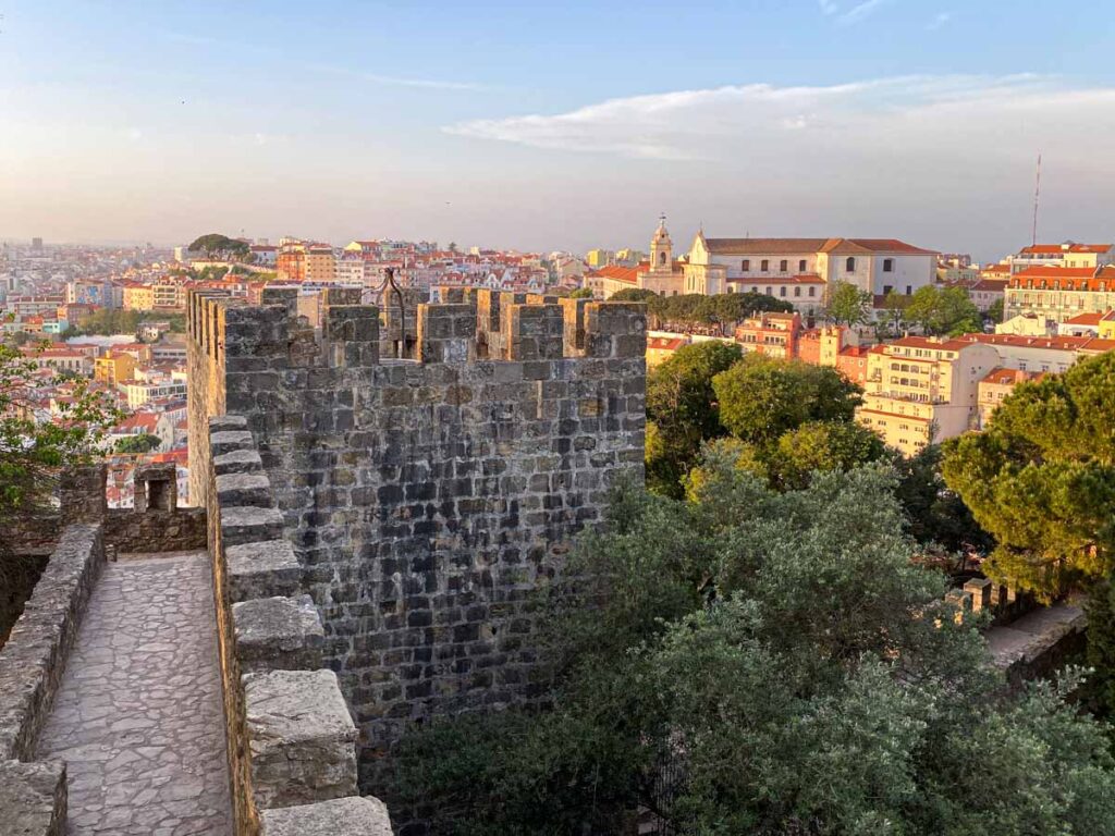A sunset walk along the castle walls of Castelo São Jorge with a beautiful view of the Lisbon cityscape.