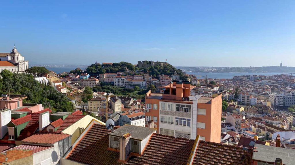 Panoramic view of Lisbon, including the Castelo de Sao Jorge and the Cristo Rei statue across the river, from Miradouro da Senhora do Monte.