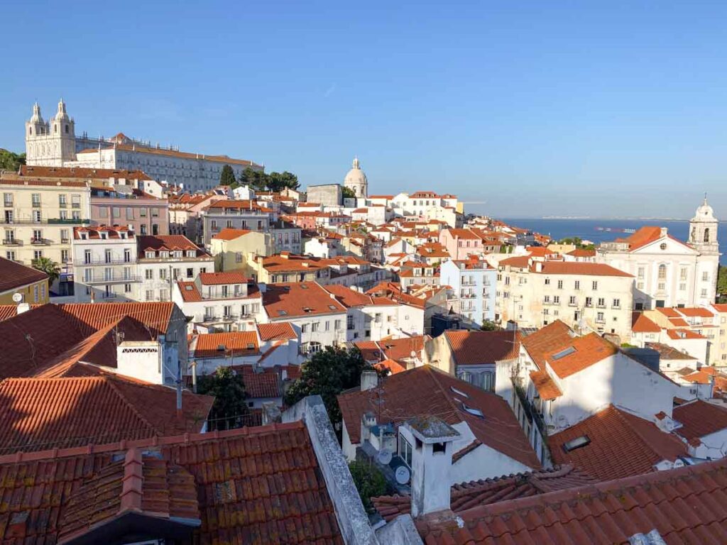 View of three churches and orange tiled roofs from Miradouro das Portas do Sol.