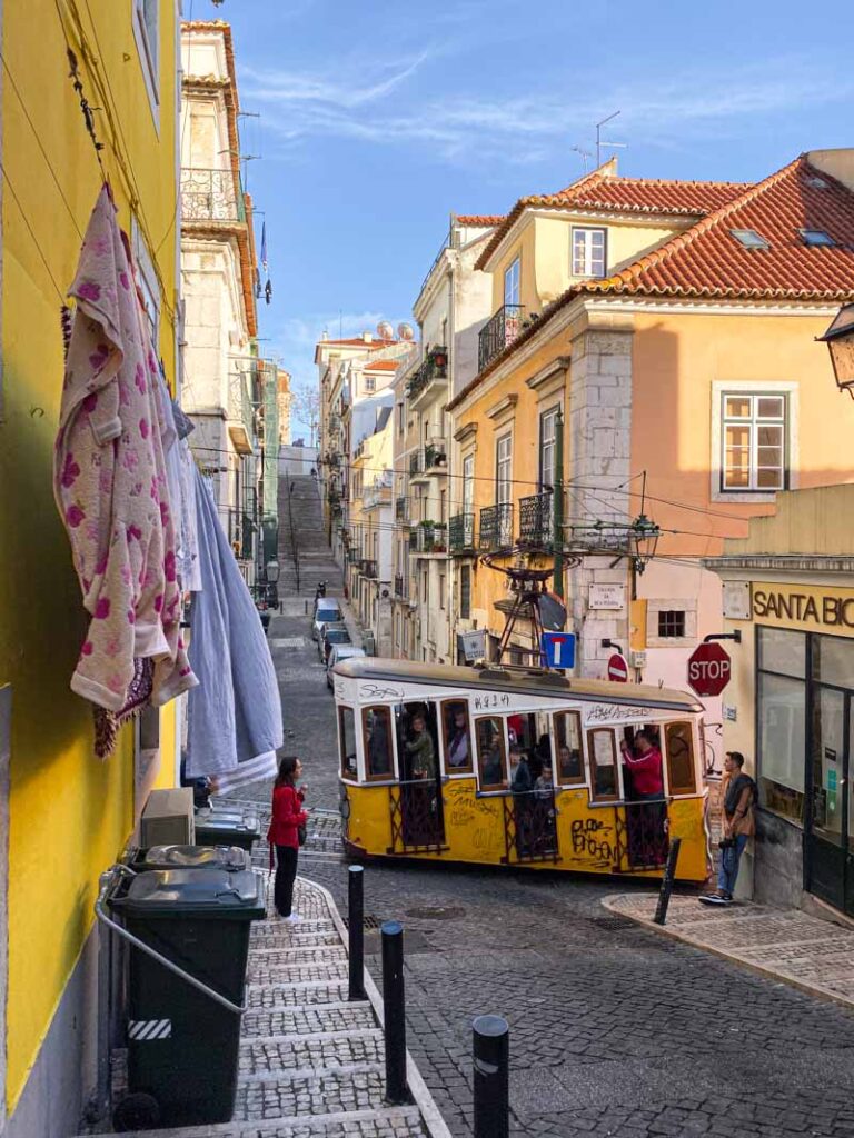 Watching the iconic yellow tram pass by from a cobblestone side street off Rua da Bica.